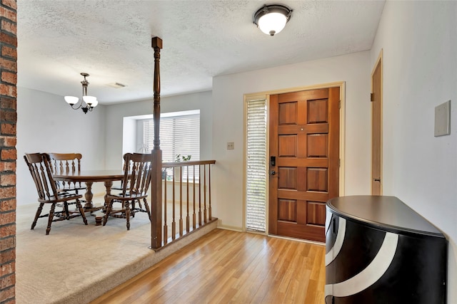 foyer featuring an inviting chandelier, light hardwood / wood-style floors, and a textured ceiling