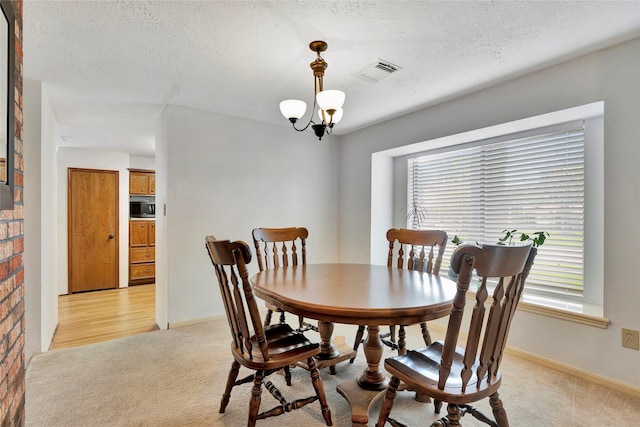 dining area featuring light carpet, a chandelier, and a textured ceiling