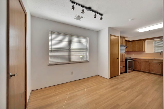 kitchen with sink, a textured ceiling, stainless steel range oven, and light hardwood / wood-style floors