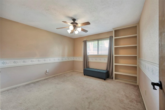 empty room featuring ceiling fan, light carpet, and a textured ceiling