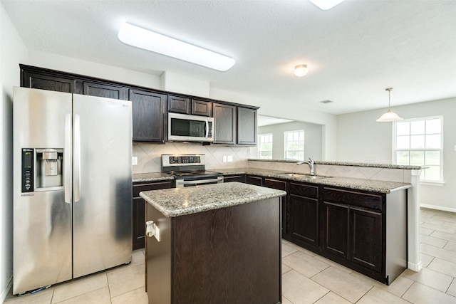 kitchen featuring a center island, sink, hanging light fixtures, dark brown cabinetry, and stainless steel appliances