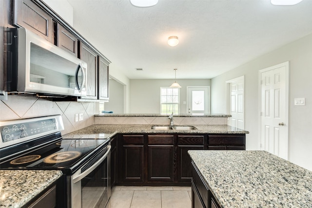 kitchen featuring tasteful backsplash, dark brown cabinetry, stainless steel appliances, sink, and light tile patterned floors