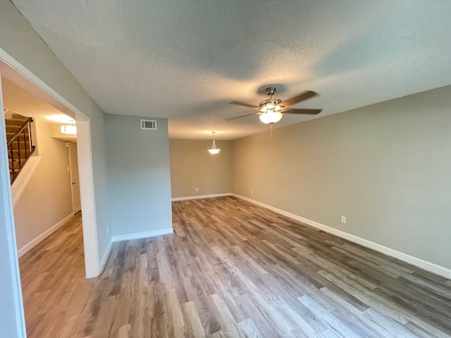 unfurnished room with ceiling fan, a textured ceiling, and dark hardwood / wood-style floors