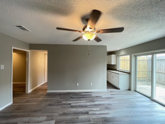 unfurnished room with plenty of natural light, a textured ceiling, ceiling fan, and wood-type flooring