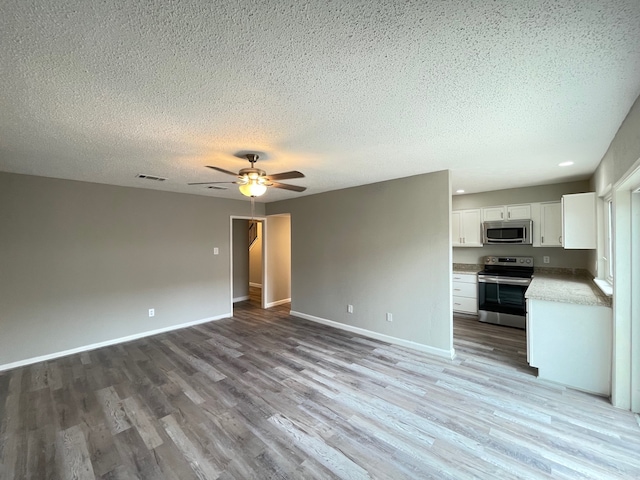 interior space featuring ceiling fan, light hardwood / wood-style floors, and a textured ceiling