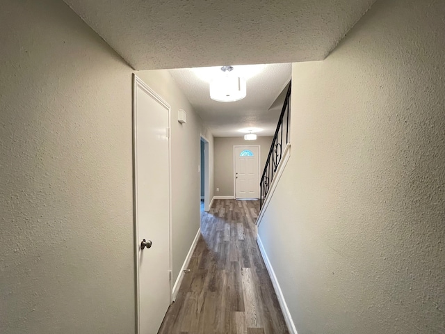 hallway with a textured ceiling and dark hardwood / wood-style floors