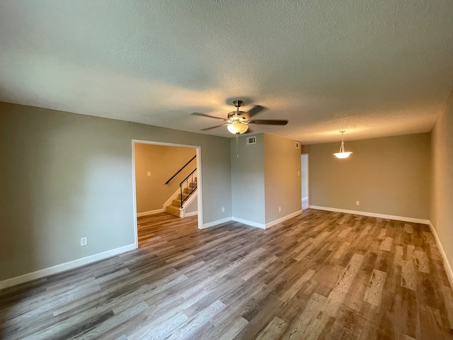 empty room with ceiling fan, a textured ceiling, and hardwood / wood-style floors