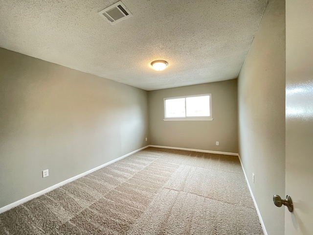 carpeted empty room featuring a textured ceiling