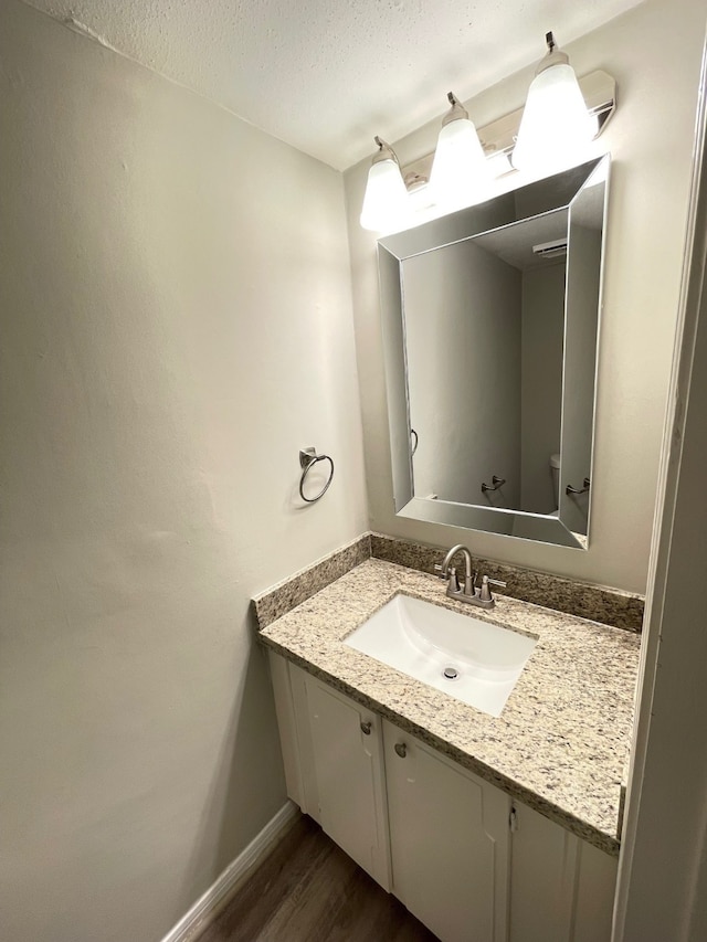 bathroom with a textured ceiling, vanity, and wood-type flooring