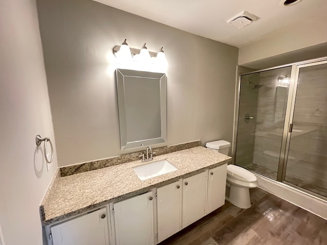 bathroom featuring toilet, vanity, a shower with door, and hardwood / wood-style flooring