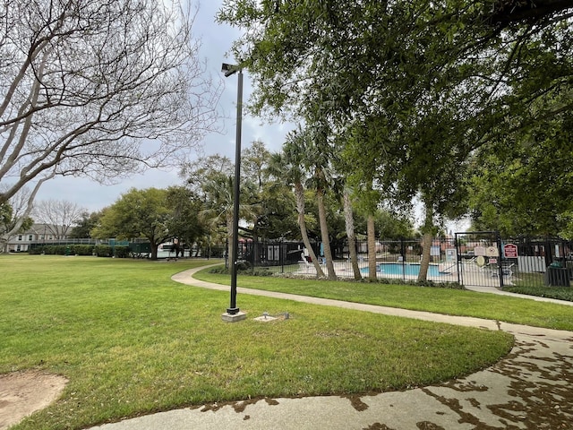 view of property's community with a swimming pool and a lawn