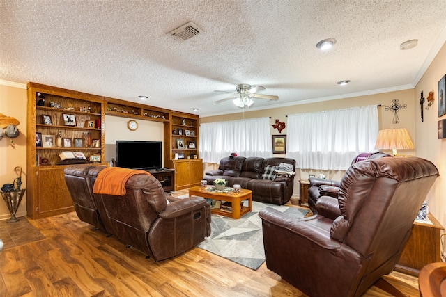 living room featuring ornamental molding, ceiling fan, a textured ceiling, and light wood-type flooring