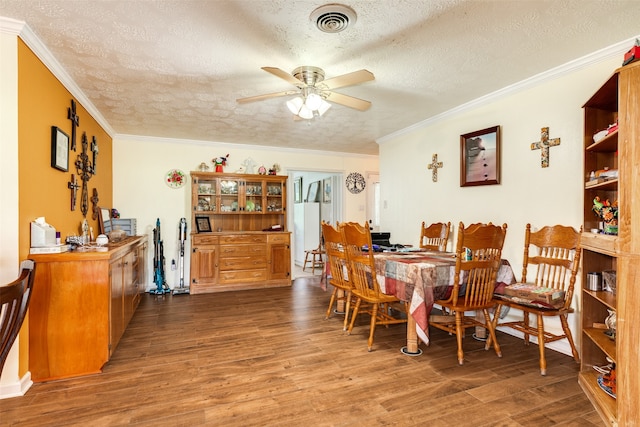 dining area featuring crown molding, dark wood-type flooring, ceiling fan, and a textured ceiling