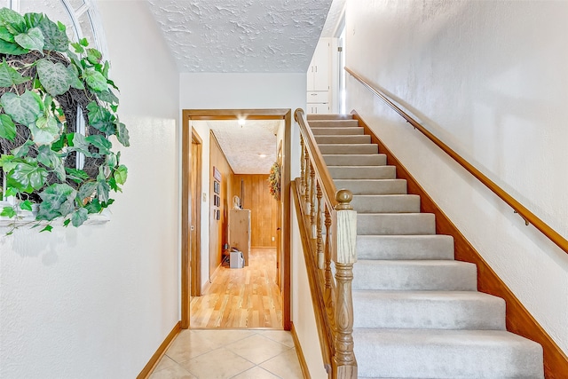 stairs featuring a textured ceiling and hardwood / wood-style flooring