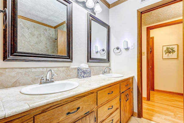 bathroom featuring a textured ceiling, vanity, wood-type flooring, and crown molding