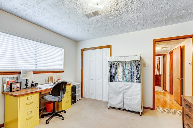 carpeted office space featuring a textured ceiling