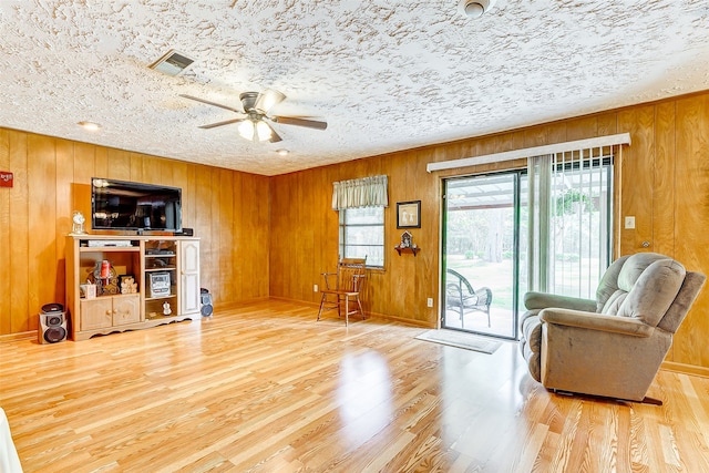 sitting room with wood-type flooring, a textured ceiling, and wood walls