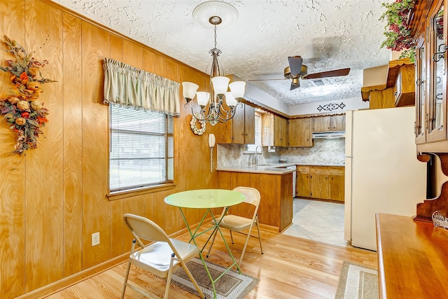 kitchen featuring tasteful backsplash, sink, decorative light fixtures, white fridge, and light hardwood / wood-style floors