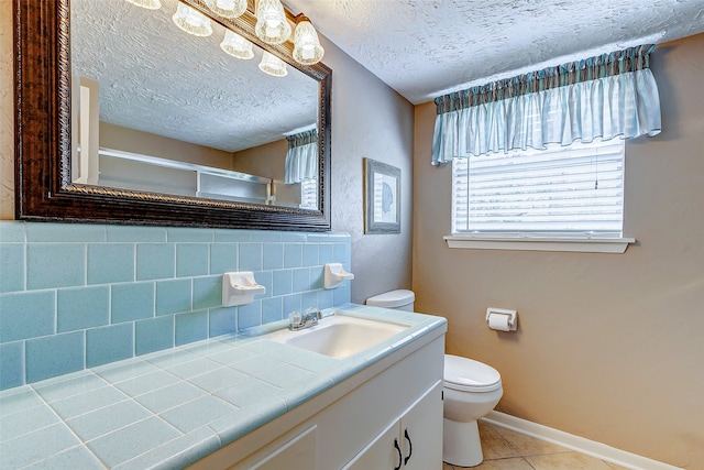 bathroom with tile patterned floors, vanity, toilet, and a textured ceiling