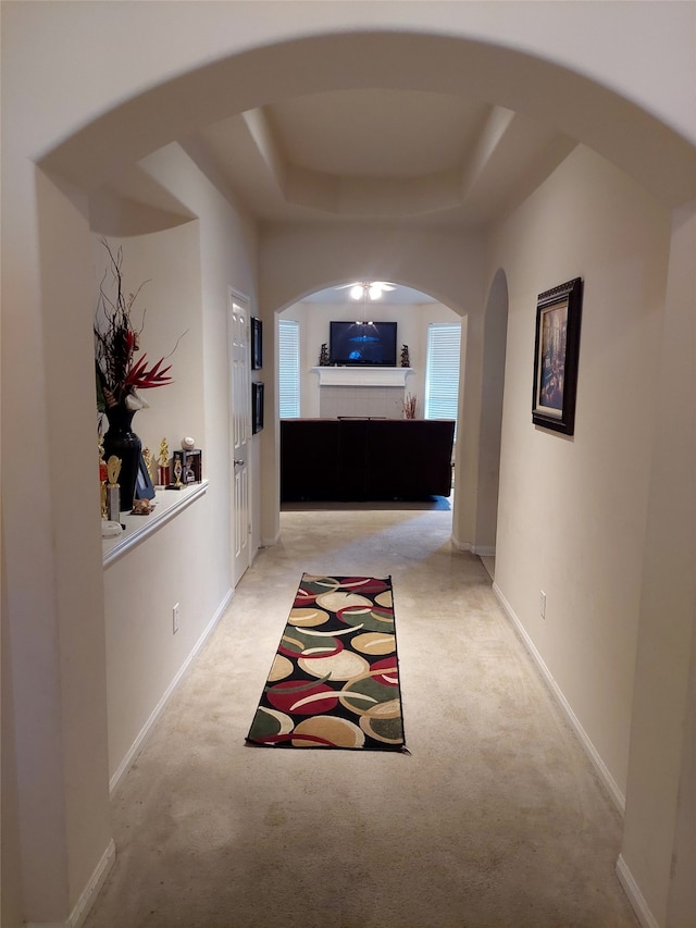 hallway featuring light carpet and a tray ceiling