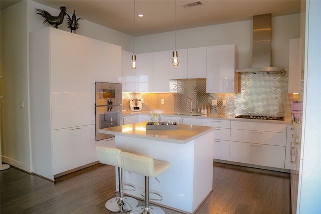 kitchen featuring sink, white cabinets, wall chimney range hood, and dark hardwood / wood-style floors