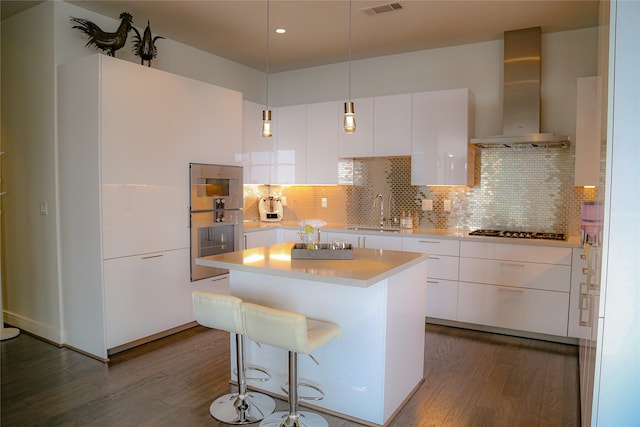 kitchen with tasteful backsplash, wall chimney range hood, sink, appliances with stainless steel finishes, and white cabinets