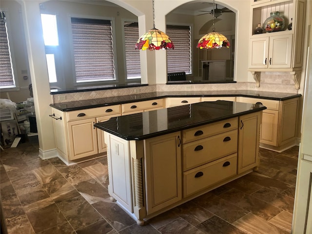 kitchen featuring a center island, decorative light fixtures, backsplash, dark tile flooring, and ceiling fan