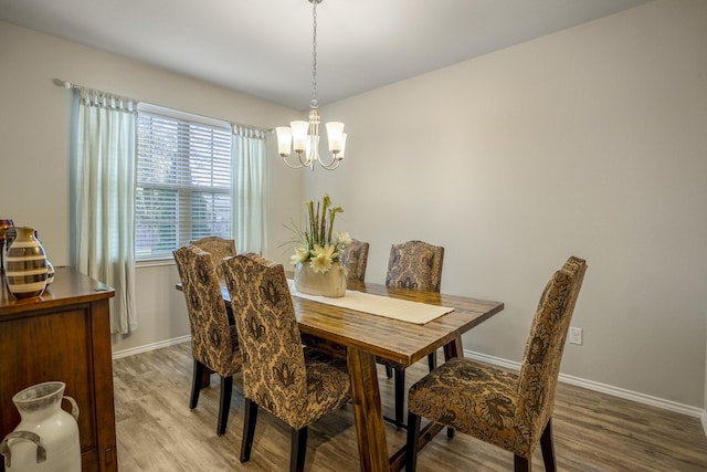 dining space with hardwood / wood-style flooring and a notable chandelier