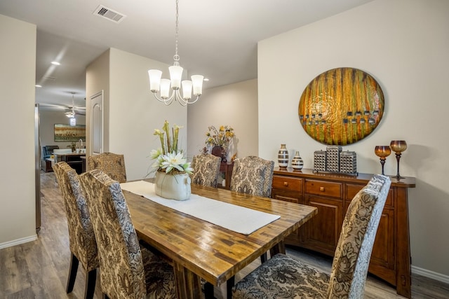 dining space with light hardwood / wood-style floors and ceiling fan with notable chandelier