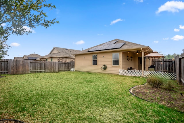 back of property with a yard and solar panels