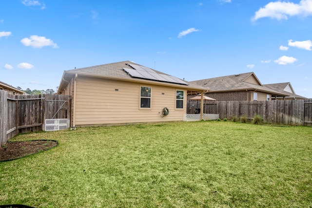 rear view of property featuring solar panels and a yard