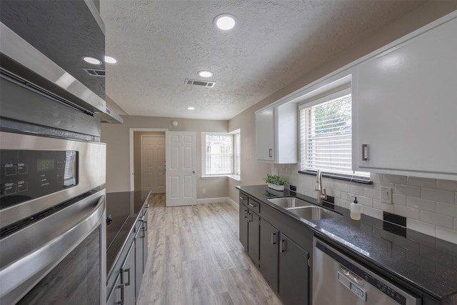 kitchen featuring visible vents, light wood-style flooring, a sink, tasteful backsplash, and stainless steel appliances