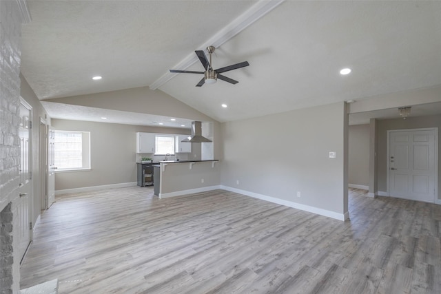 unfurnished living room with a ceiling fan, lofted ceiling with beams, baseboards, and light wood-type flooring