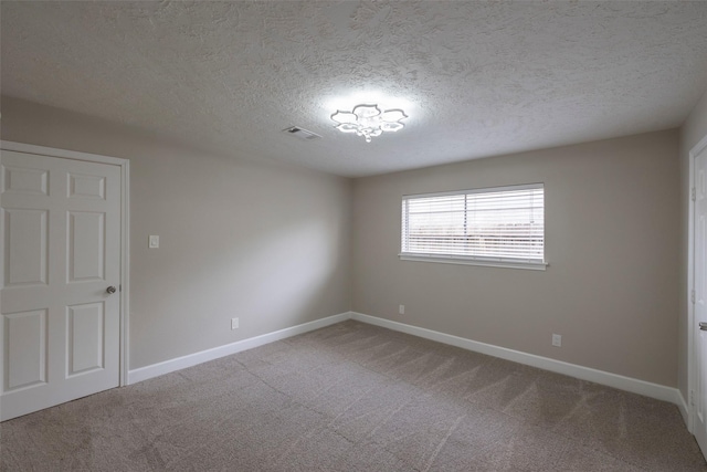 carpeted spare room featuring baseboards, visible vents, and a textured ceiling