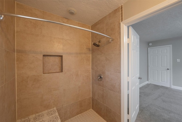 full bathroom with a stall shower, a textured ceiling, and baseboards