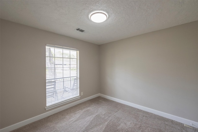 unfurnished room featuring carpet flooring, baseboards, visible vents, and a textured ceiling