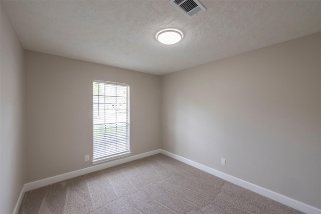 unfurnished room featuring visible vents, carpet flooring, a textured ceiling, and baseboards