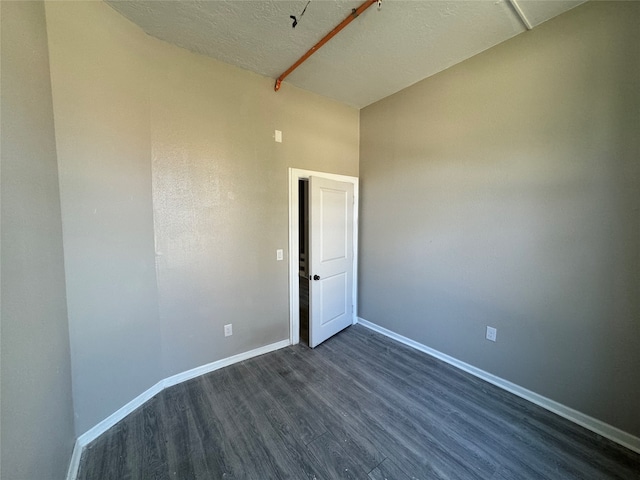 empty room with a textured ceiling and dark wood-type flooring