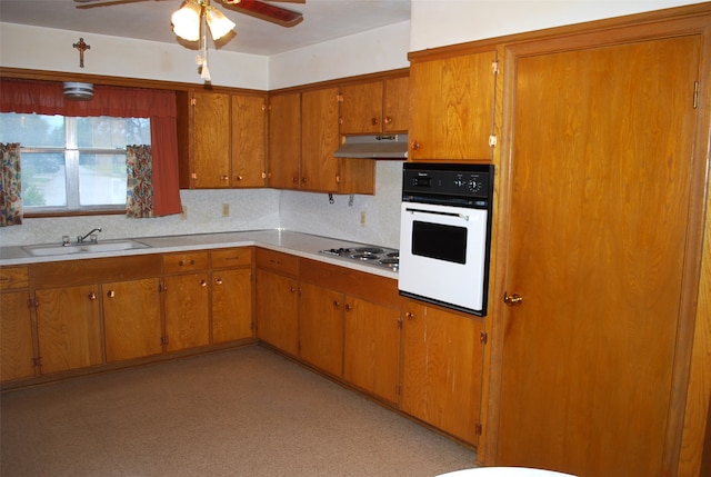 kitchen featuring backsplash, stainless steel gas cooktop, ceiling fan, sink, and oven