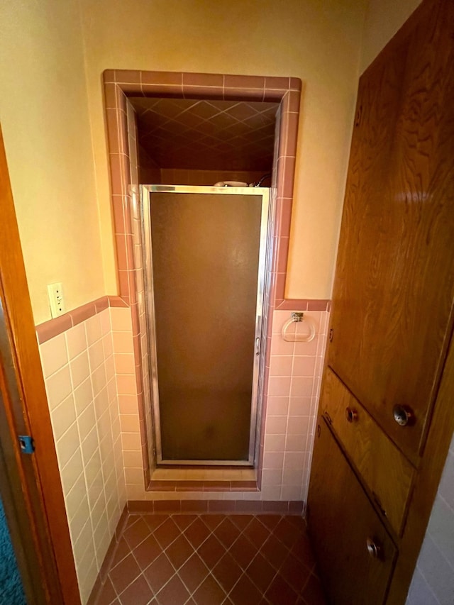 bathroom featuring a shower with shower door, tile walls, and tile flooring