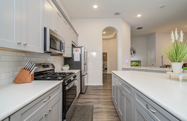 kitchen featuring sink, gray cabinetry, hardwood / wood-style floors, appliances with stainless steel finishes, and backsplash