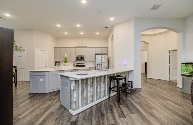 kitchen featuring gray cabinetry, dark hardwood / wood-style floors, appliances with stainless steel finishes, sink, and a breakfast bar area