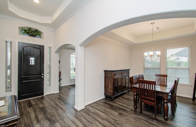 dining space with plenty of natural light, a tray ceiling, a notable chandelier, and dark hardwood / wood-style floors