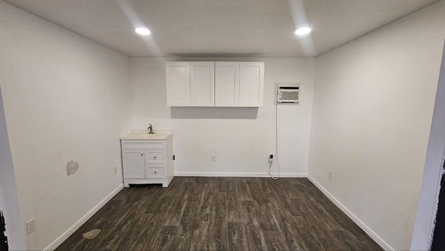 laundry area featuring sink, a wall mounted air conditioner, and dark hardwood / wood-style floors