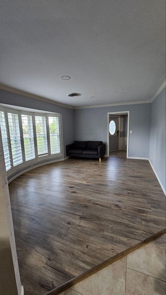 unfurnished living room featuring dark wood-type flooring and ornamental molding