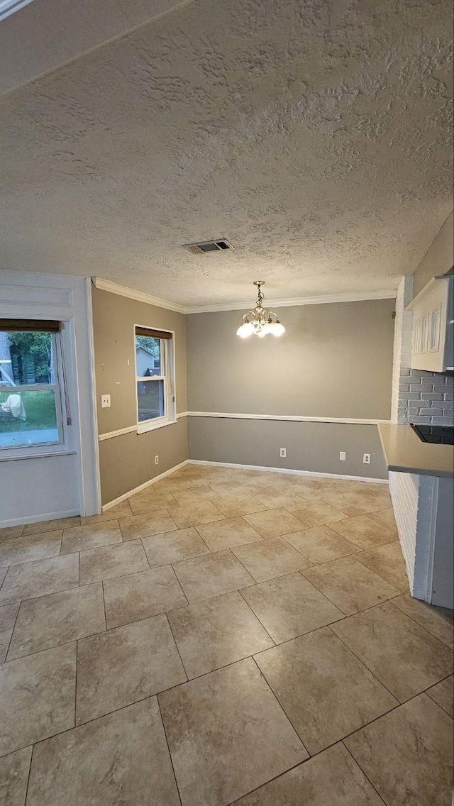 unfurnished dining area featuring crown molding, a notable chandelier, and a textured ceiling