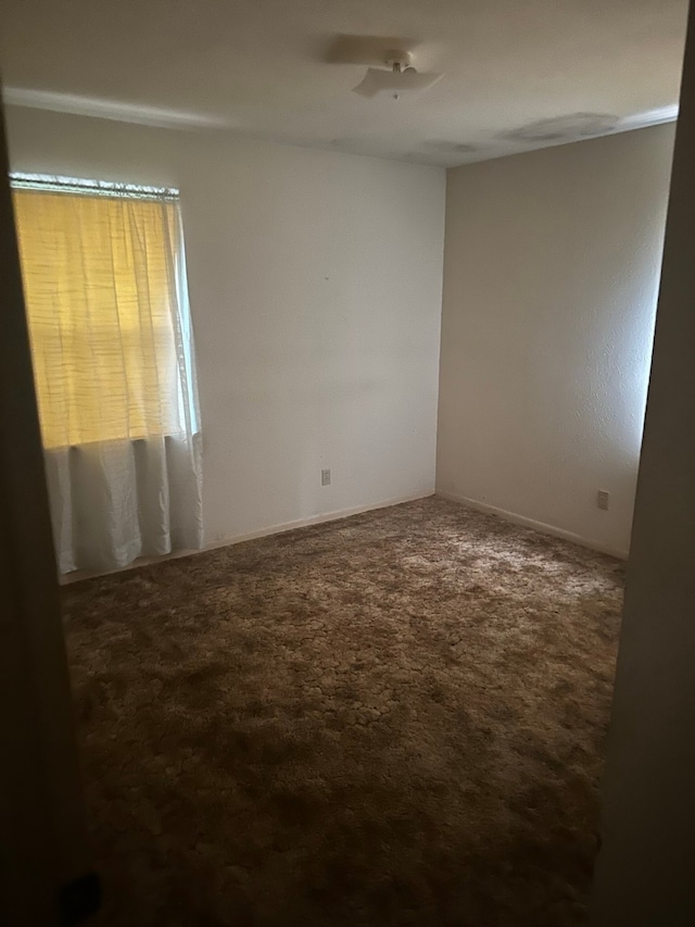 spare room with dark colored carpet and ceiling fan