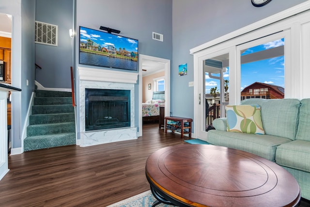 living room featuring a high ceiling, dark hardwood / wood-style floors, and a fireplace