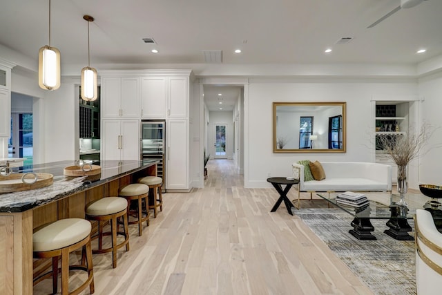 kitchen featuring white cabinets, dark stone counters, and light wood-type flooring