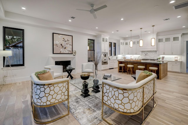 living room with ceiling fan, light wood-type flooring, and sink